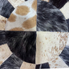 Close-up of a patchwork cowhide rug with brown, black, and beige patches.