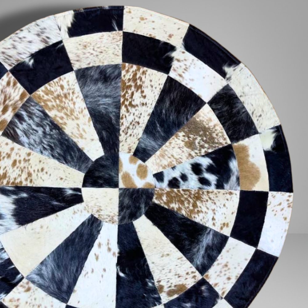 Round cowhide rug with black, white, and brown pattern on a gray background