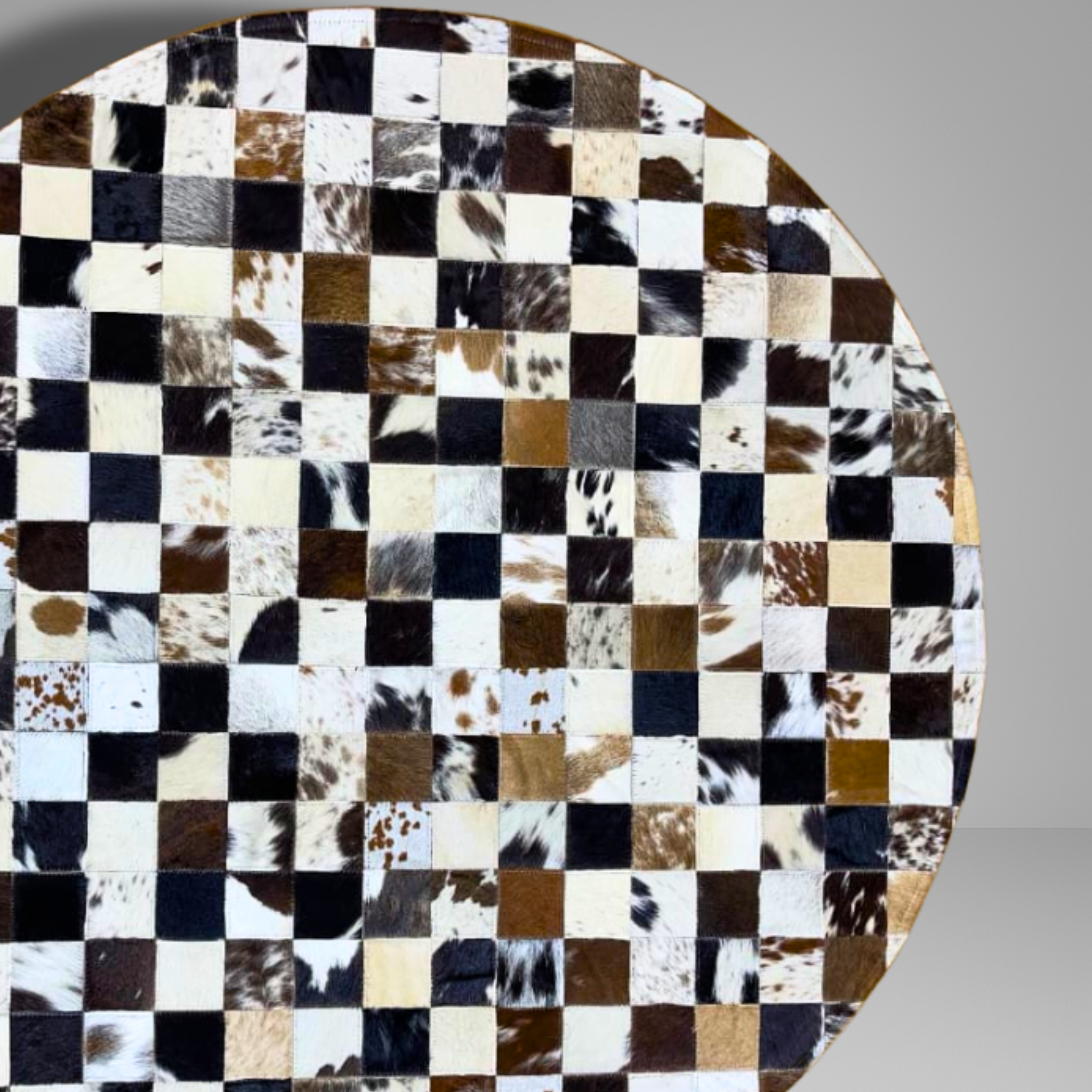 Round table top with a checkered pattern of cowhide leather squares on a gray background