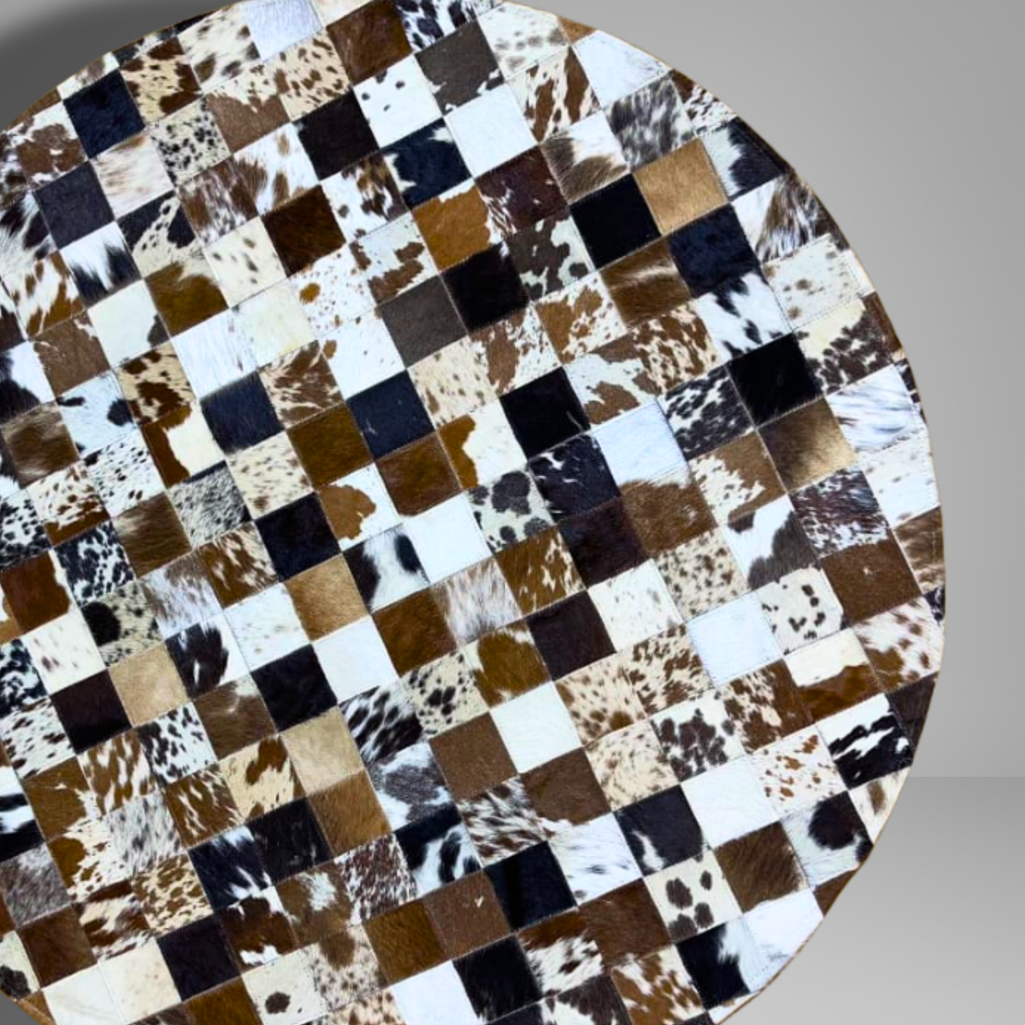 Round table with a checkered pattern made of cowhide leather on a gray background