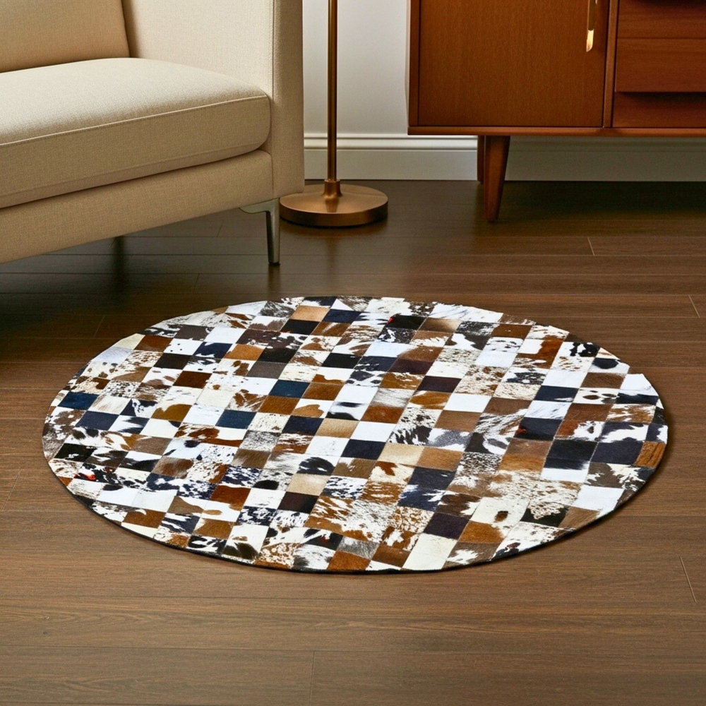 Round patchwork rug on a wooden floor with a beige sofa and wooden cabinet in the background.