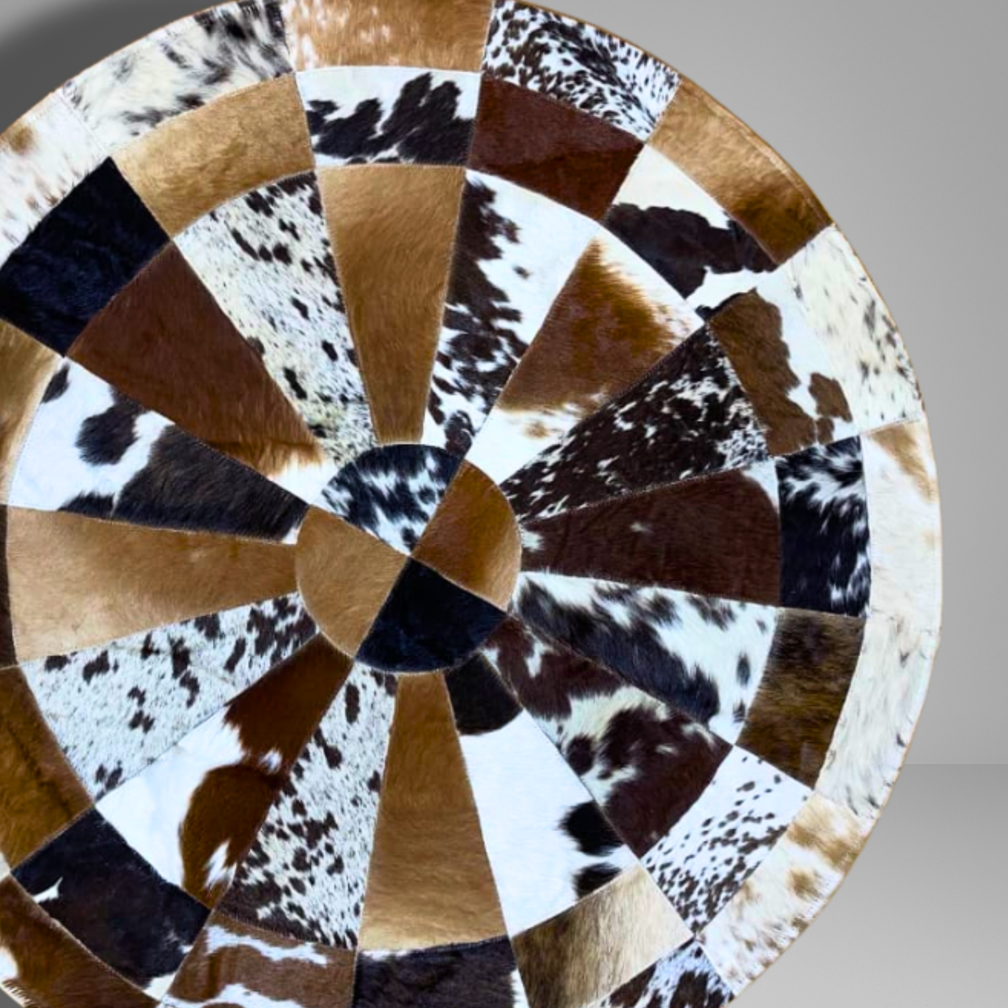 Round cowhide rug with a patchwork pattern on a gray background