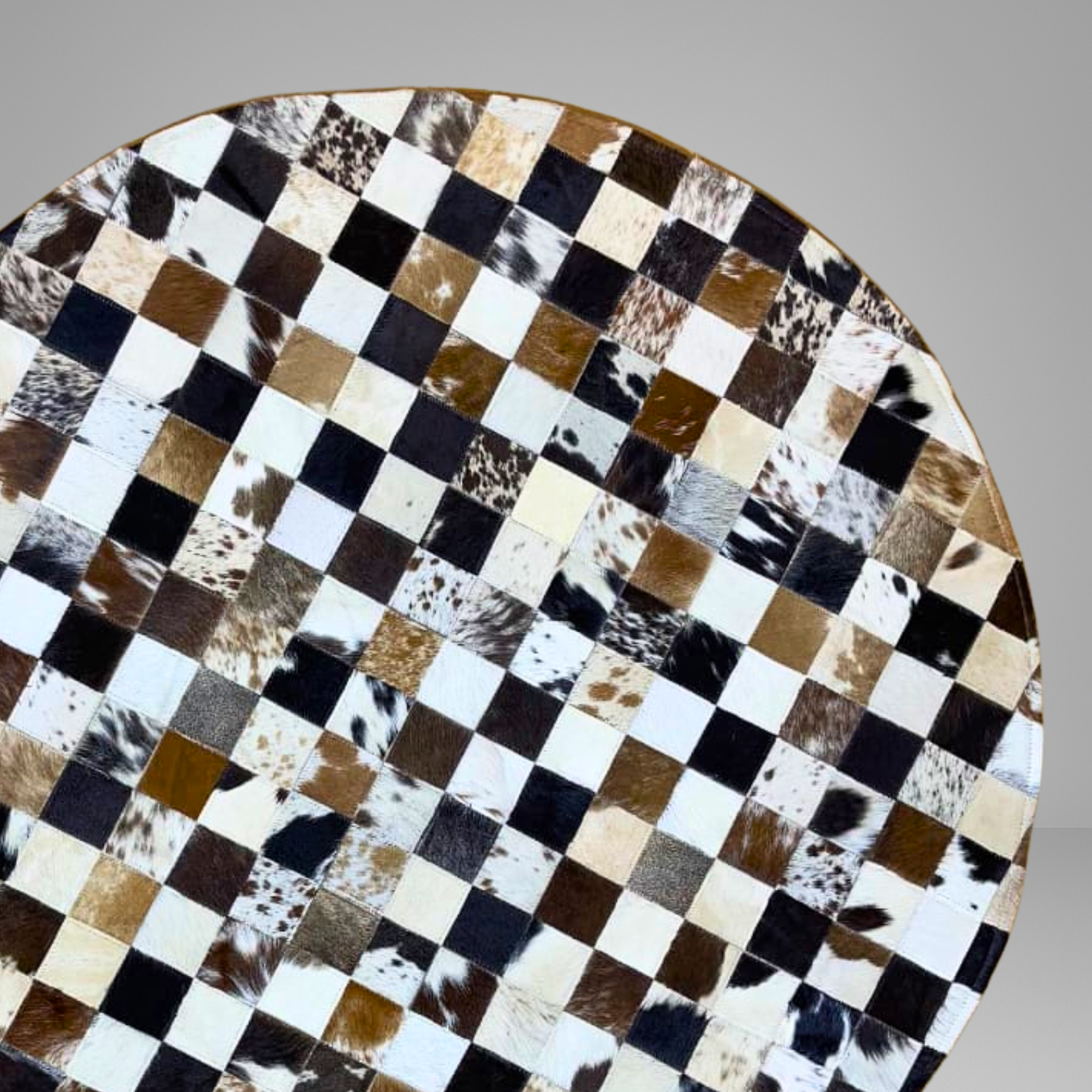 Round table with a checkered pattern made of different colored leather squares on a gray background