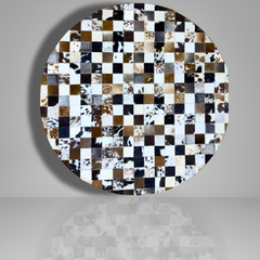 Round table top with a checkered pattern of cowhide leather squares on a gray background