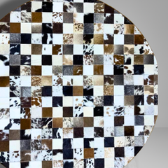 Round surface with a checkered pattern of cowhide leather squares on a gray background